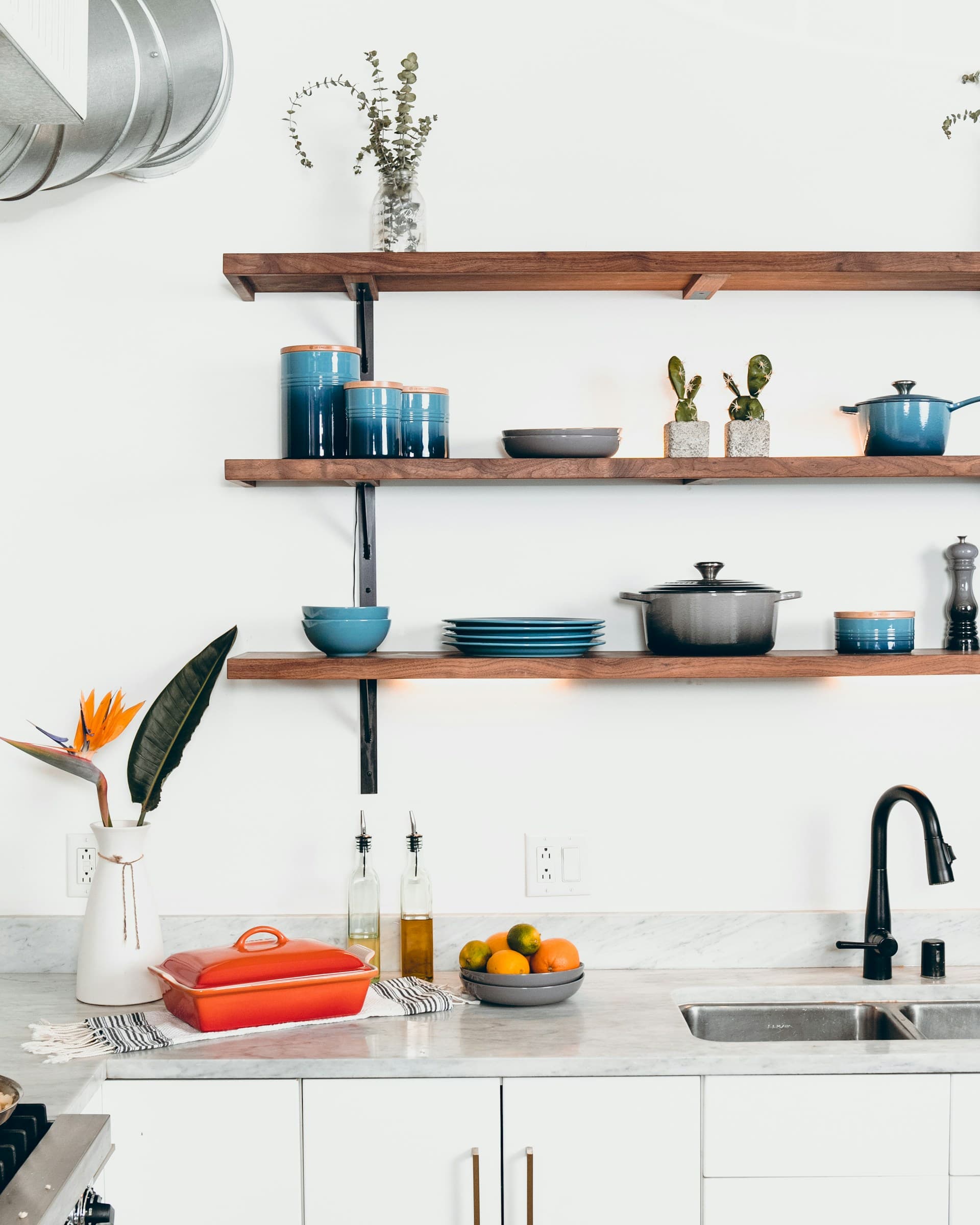 Modern kitchen shelves with ceramic dishes, pots, and indoor plants arranged neatly